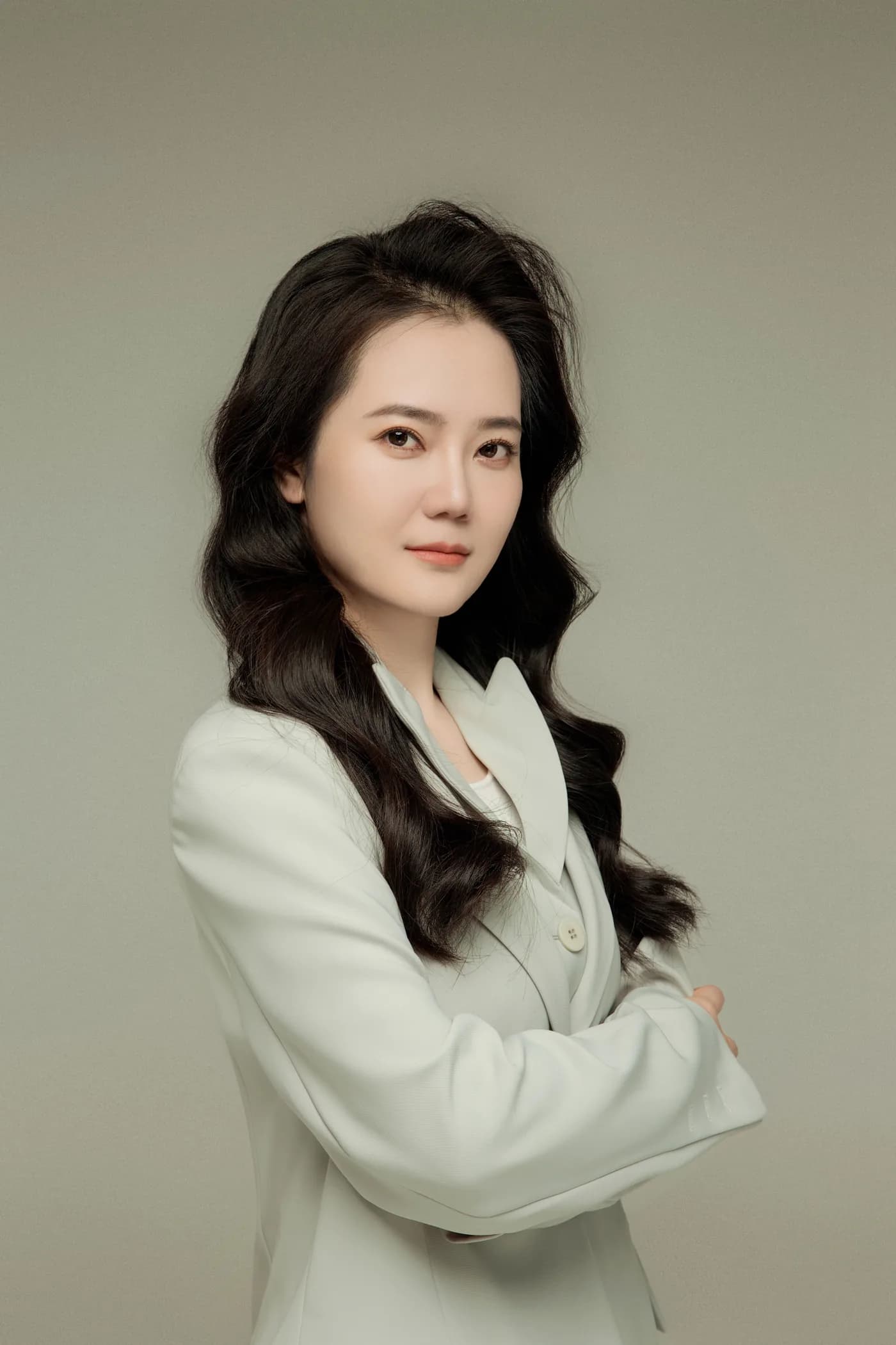 Retrato profesional de Teresa Gao con traje blanco.